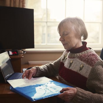 Erica, who lives with chronic lymphocytic leukaemia (CLL), sits at her desk, filling paper into a folder.