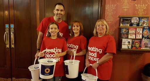 A group of fundraisers stand in a theatre with fundraising buckets. They're attending the musical "The Girls", written by Gary Barlow about the Calendar Girls.
