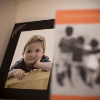 A framed photo of Hugo, a young blonde boy in remission from childhood leukaemia, leaning on a log, looking at the camera.