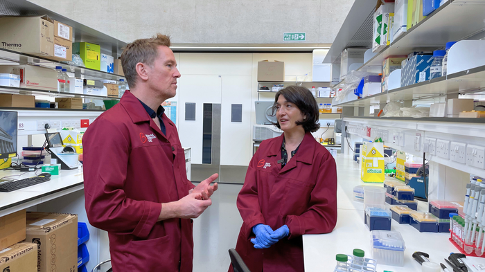 Female researcher showing a man things in a lab.