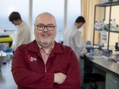 Professor Tonks stood in the lab, with his arms folded, wearing a red Blood Cancer UK lab coat.