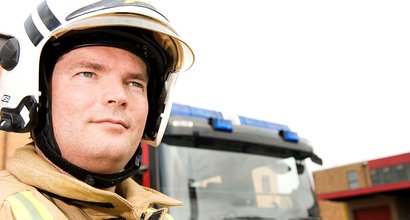Ally wearing fire uniform, standing in front of a fire engine