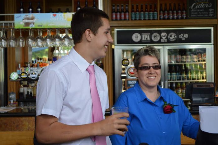 Angie Sharp, who lives with CML, stands in a pub smiling with a friend.
