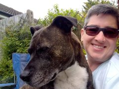 Angie Sharp who lives with CML, sits smiling in the garden with a large dog on her lap.