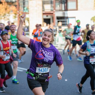 Female Blood Cancer UK runner celebrating with one arm in the air