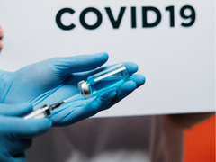 A close up of someone's hands with blue gloves on - they are squeezing a syringe into a vile.