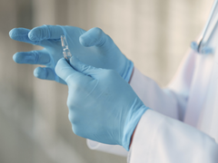 A doctor with blue gloves holding a medical implement.
