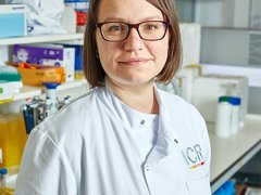 Dr Radzisheuskaya stood in the lab smiling wearing a white lab coat.