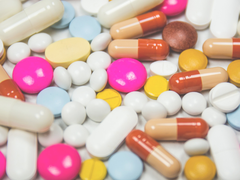 A selection of different white pills and colourful capsules close up.