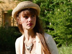 A young woman - Emma - wearing a small straw hat in a garden outside.