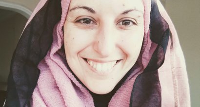 A selfie of a woman (Federica) smiling, wearing a pink and black headscarf