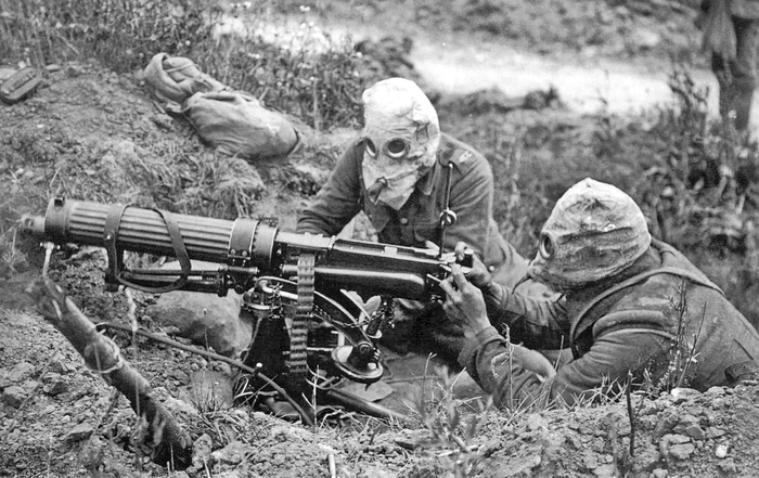 World War One image of man with rudimentary gas mask on preparing a machine gun on the battlefield.