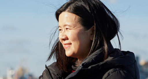 Jacqueline, a blood cancer patient, looking into the sun outdoors with a black coat on.