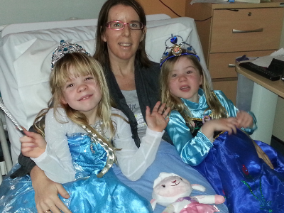 Jane Leahy, blood cancer patient, in a hospital bed with her daughters, dressed as princesses.