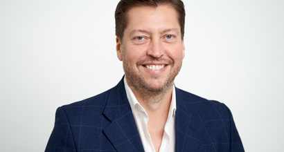 Matthew Wilson, a member of the Board, smiling against a plan white background.