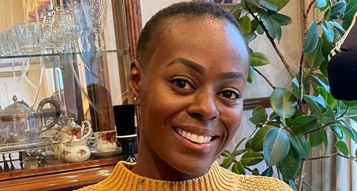 Nadine, wearing a yellow jumper and smiling