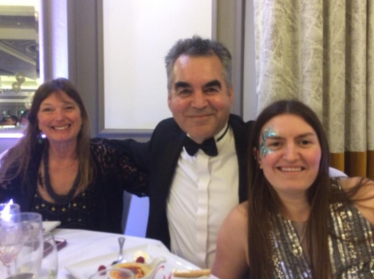 Nicky, a woman who lives with chronic lymphocytic leukaemia (CLL) and participated in a clinical trial, sits with family at a restaurant table.