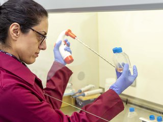 Blood Cancer UK funded researcher Dr Farhat Latif Khanim from the University of Birmingham in a laboratory holding a pipette and sample jars.
