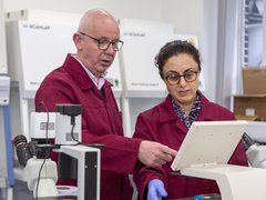Two researchers stand in a laboratory. They are examining the screen of a piece of equipment.