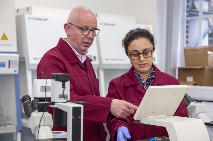 Two researchers stand in a laboratory. They are examining the screen of a piece of equipment.
