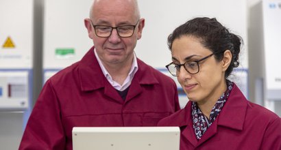 Two Blood Cancer UK Researchers standing side-by-side looking at a screen together.