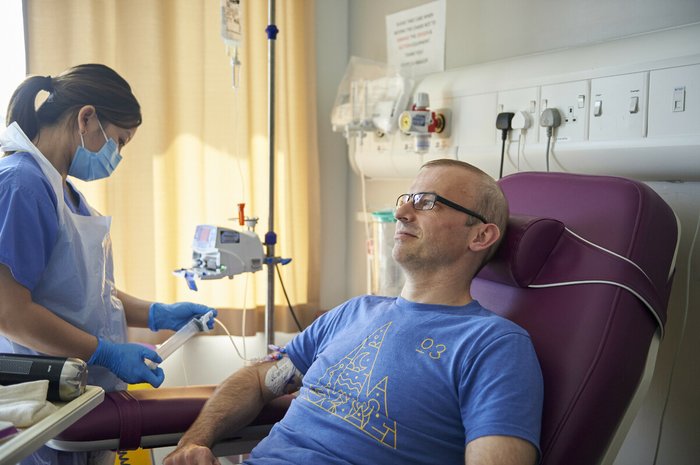 A healthcare professional giving treatment to a man in hospital.