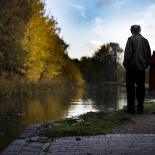Louise, a Blood Cancer UK ambassador that has hodgkin lymphoma, standing next to a man with their backs to the camera looking over a lake.