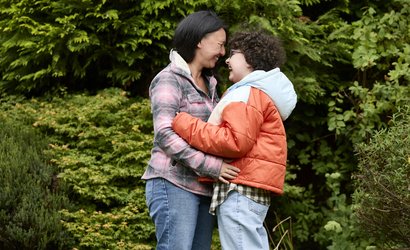 Alyssa and mum, Kiona, outside, facing each other and laughing as they embrace.