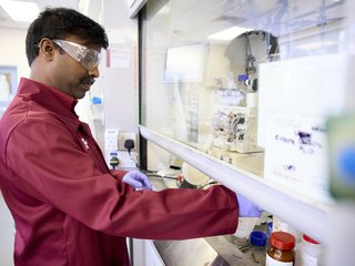 A researcher working in a lab, wearing goggles.