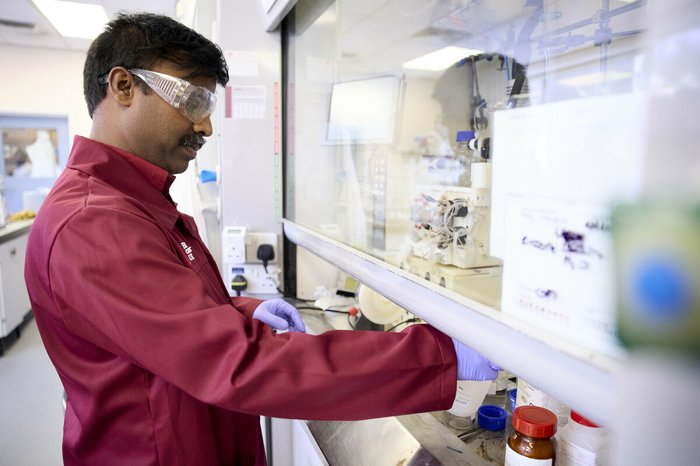 A researcher working in a lab, wearing goggles.