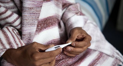 A close up of two hands holding a thermometer.