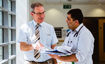 Researcher Professor Peter Hillmen who is funded by Blood Cancer UK talking with a colleague over a booklet of notes.