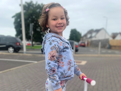 Five-year-old Mila Sneddon standing with her scooter smiling at the camera.