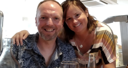 Jude with her arm around husband Nige, who was diagnosed with non-Hodgkin lymphoma, smiling at the camera.