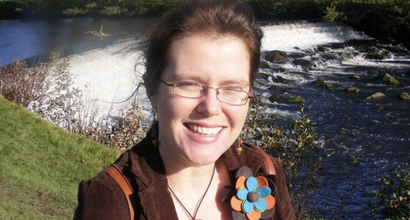 Joanna, who was diagnosed with chronic myeloid leukaemia (CML), standing beside a river smiling at the camera.