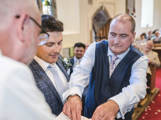 Lawrence, who was diagnosed with Hodgkin lymphoma, standing in front of a church congregation wearing a suit.