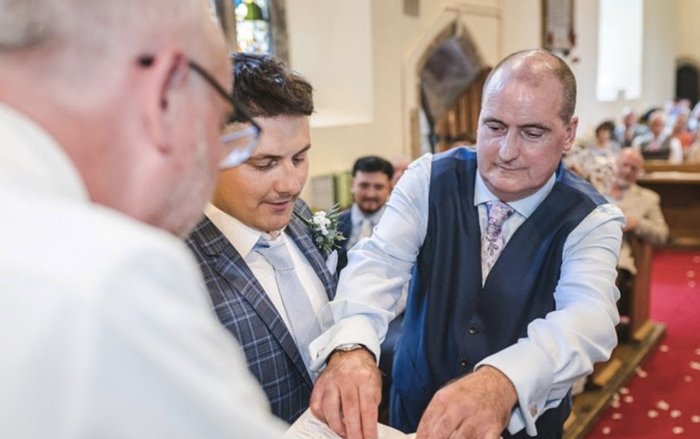 Lawrence, who was diagnosed with Hodgkin lymphoma, standing in front of a church congregation wearing a suit.