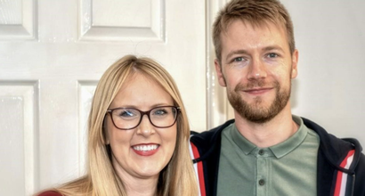 Emma, who was diagnosed with acute lymphoblastic leukaemia (ALL), smiling next to her partner in front of a wooden door.