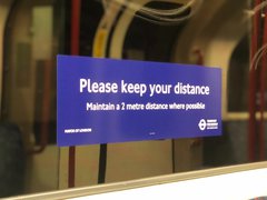 Transport for London sticker on the window of an underground train displaying text to keep a 2 metre distance from others.