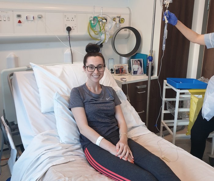 Young women sitting on hospital bed receiving treatment