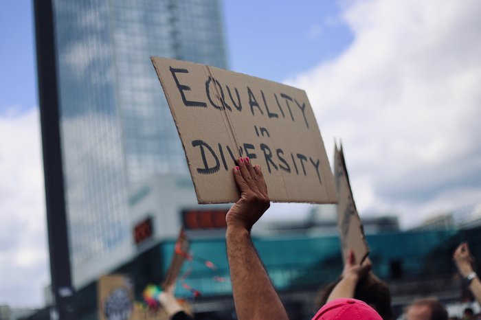 At a protest march, marchers hold up a sign with Equality and Diversity written on it.