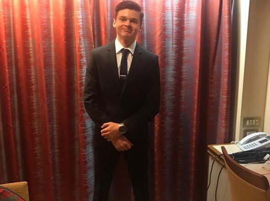A man - Ed Garside - in a hotel room wearing a suit