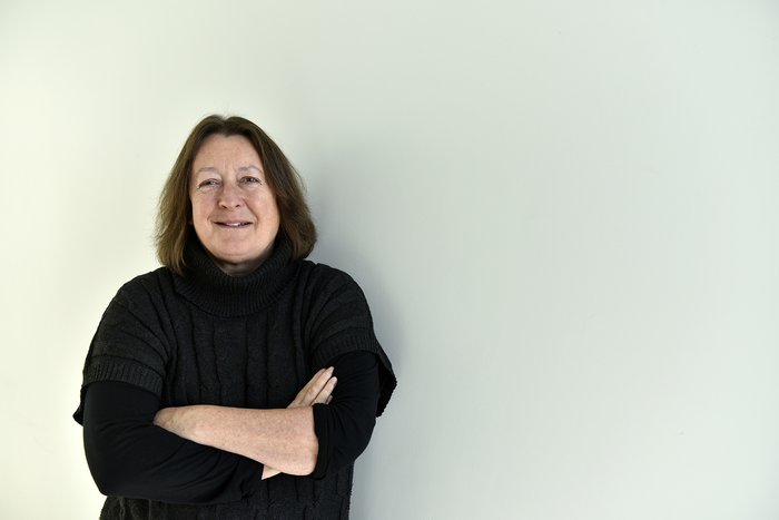 Professor Constanze Bonnifer stands smiling with her arms crossed in front of a white wall.