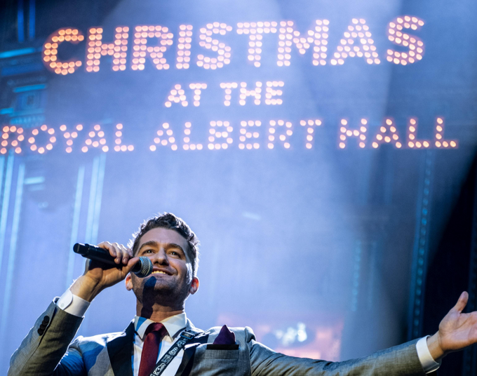 A singer finishes a song, arms outstretched, onstage at Christmas with the Stars at the Royal Albert Hall