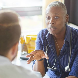 Doctor with a stethoscope around their neck talks to patient about their blood cancer.