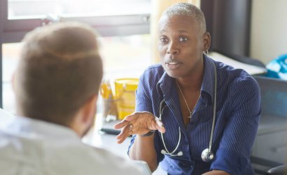 Doctor with a stethoscope around their neck talks to patient about their blood cancer.