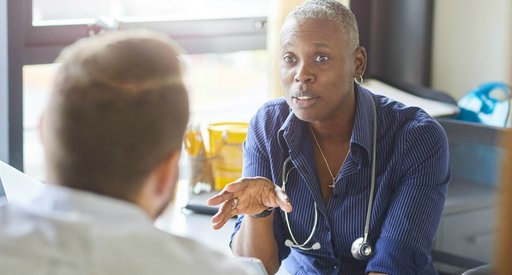 Doctor with a stethoscope around their neck talks to patient about their blood cancer.