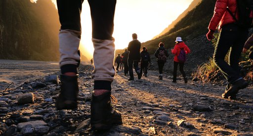 Low down photo of people walking away from the camera into the sunset in a rural location.