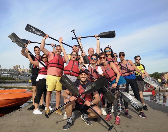 The itsu dragon boar team at the Dragon Boat race pose together with oars held aloft.
