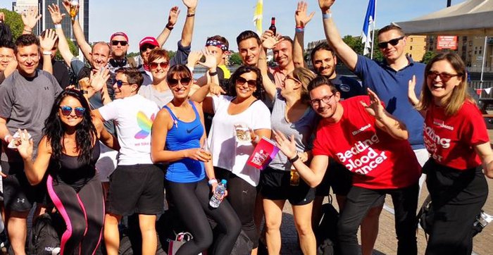 A group of Itsu employees holding their hands in the air, outside in the sun, supporting a Blood Cancer UK event.